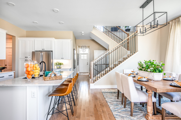Modern kitchen and dining area with a white island, stainless steel appliances, and a staircase leading to the upper level. bright and spacious with natural light.