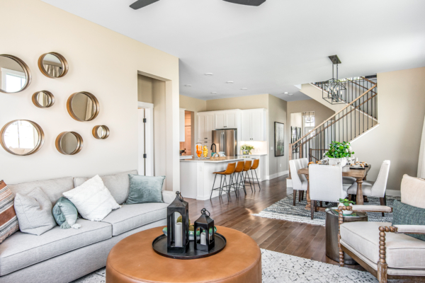 Modern living room with a beige sofa, round mirrors on the wall, and an open plan layout leading to a kitchen with a breakfast bar.
