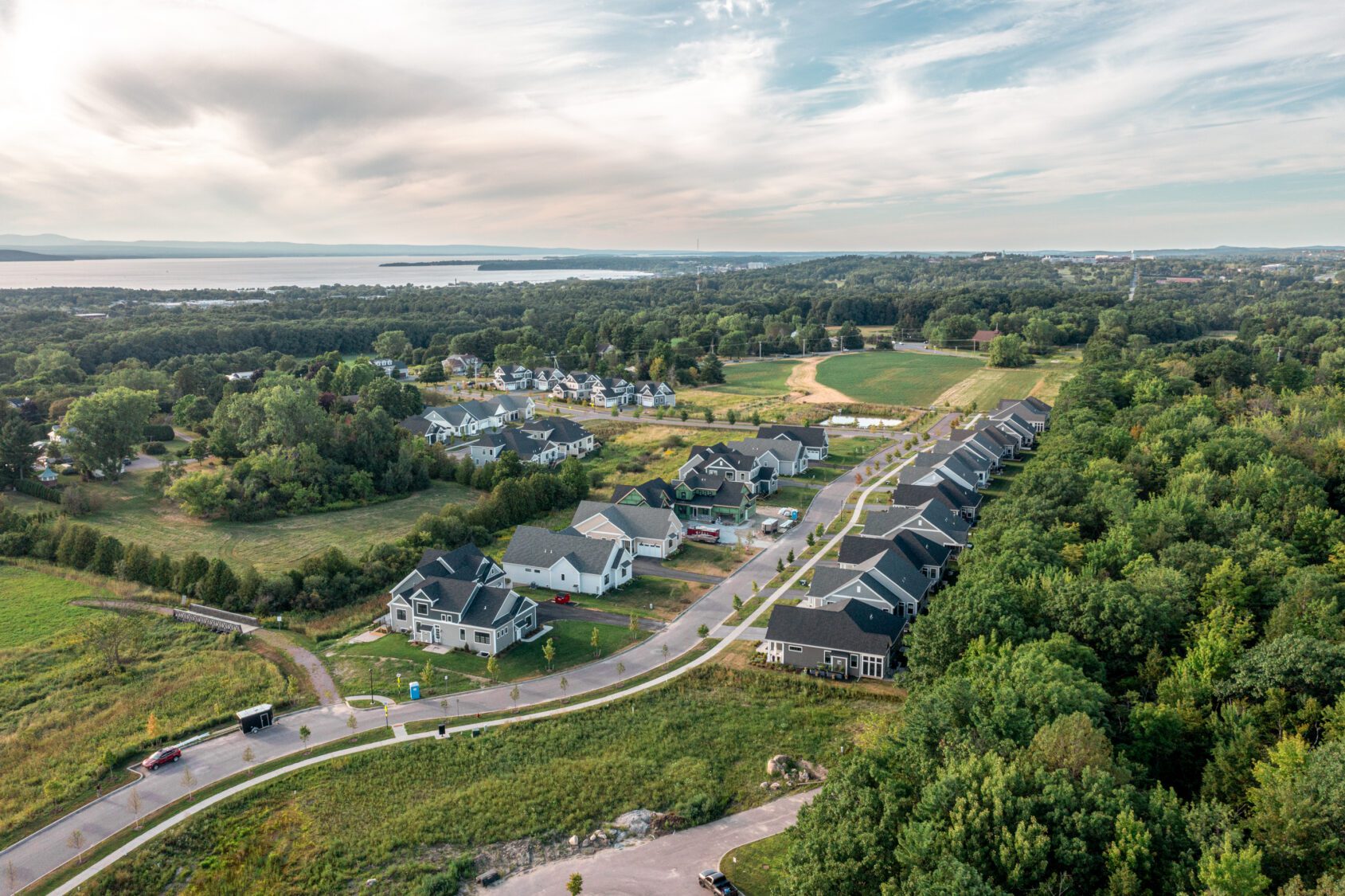 Aerial view of Spear Meadows, a suburban neighborhood with houses, trees, fields, and distant water.