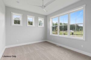 Bright, empty room with gray walls, large windows, beige carpet, and a modern ceiling fan at 30 Halcyon Drive.