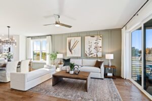 Modern living room with neutral tones, large windows, wall art, and a wooden coffee table with plants.