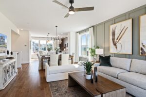 Modern living and dining room with light furniture, wood floors, large windows, and framed artwork on the wall.