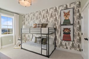 Children’s bedroom with metal bunk beds, forest wallpaper, and framed fox and red panda art on the wall.
