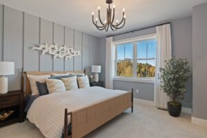 Modern bedroom with a large bed, wall art, a window with a view, and a potted plant in the corner.