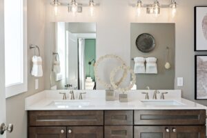 Modern bathroom with double sinks, dark wood cabinets, and decorative mirrors and wall art.