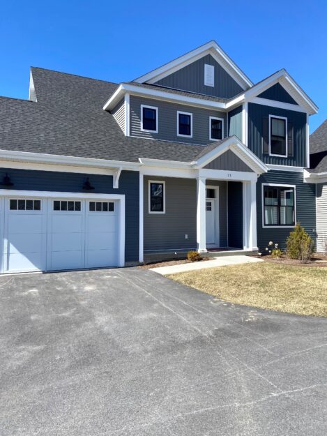 Two-story modern house at 71 Elm Street with blue siding, white trim, and a double garage on a sunny day.