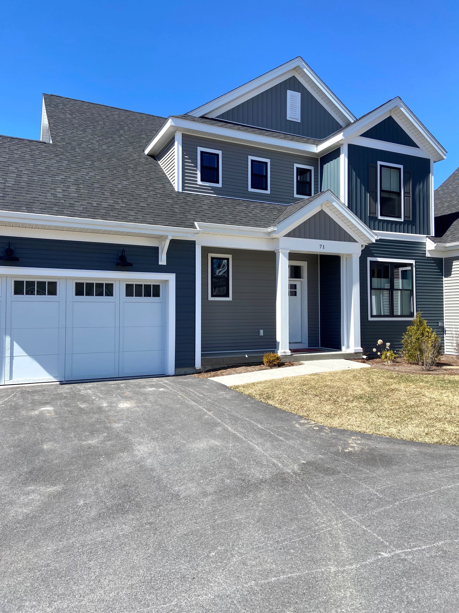 Two-story modern house at 71 Elm Street with blue siding, white trim, and a double garage on a sunny day.