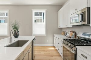 Modern kitchen at 71 Elm Street with white cabinets, stainless appliances, and a center island with sink and plant.