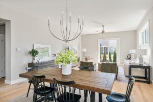 Modern dining room at 71 Elm Street with a wooden table, black chairs, and chandelier, opening to a bright living area.
