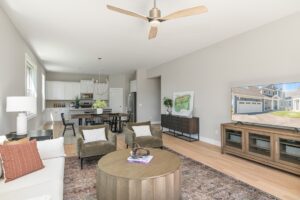 Bright, modern open-concept living room and kitchen at 71 Elm Street, with neutral decor and a TV displaying a house.