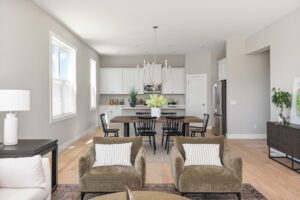 Modern open-concept living room and kitchen at 71 Elm Street with neutral tones, wooden dining table, and white cabinetry.