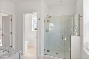 Modern bathroom at 71 Elm Street with a glass shower, toilet, and granite countertop under bright natural light.