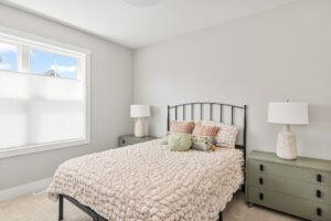 Sunny bedroom at 71 Elm Street with a cozy bed, green nightstands, and two lamps against light-colored walls.