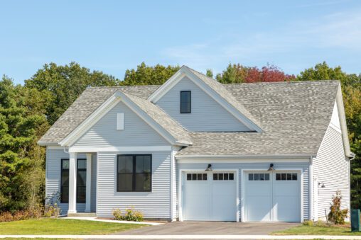 Modern single-story house at 385 Beaudry Lane with gray siding, black trim, and a double garage under a clear blue sky.