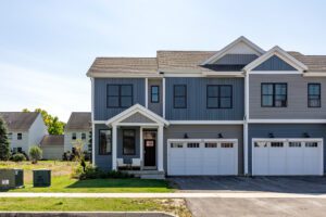 A modern two-story townhouse at 68 Eden Lane with blue siding, garage, and a small front porch on a sunny day.