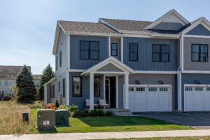 Blue two-story duplex with white trim at 68 Eden Lane, porch chairs, and a green utility box on a suburban street.