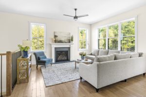 Bright living room at 385 Beaudry Lane with a gray sectional, blue chair, fireplace, large windows, and wood floors.