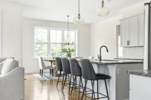 Modern kitchen at 385 Beaudry with gray bar stools, island, pendant lights, and dining area near sunlit windows.