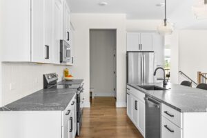 Modern kitchen at 385 Beaudry Lane with white cabinets, stainless steel appliances, and black countertops on wood floors.