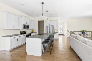 Modern kitchen at 385 Beaudry Lane with white cabinets, black countertops, island barstools, and stainless appliances.