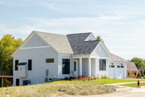 A modern white house with a gray roof at 385 Beaudry Lane, featuring a porch and attached garage on a sunny day.