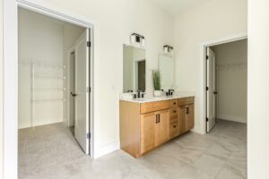 Modern bathroom at 385 Beaudry Lane with a wooden vanity, two mirrors, and doors to walk-in closets.