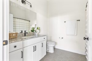Bright modern bathroom at 385 Beaudry Lane with white cabinets, granite countertop, and hexagon tile floor.