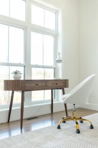A modern desk and white chair sit by large windows in a bright, minimalist room at 385 Beaudry Lane.