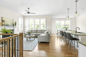 Bright open living room and kitchen at 385 Beaudry Lane with large windows, gray sofa, and modern decor.