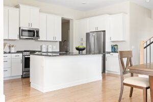 Modern white kitchen at 68 Eden Lane with stainless steel appliances, an island, and wooden flooring.