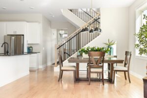 Modern dining area at 68 Eden Lane with wooden table, four chairs, and plants beside a staircase in a bright open kitchen.