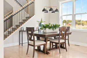 Modern dining area at 68 Eden Lane with wooden table, four chairs, potted plant centerpiece, and nearby staircase.