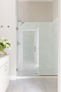 Modern bathroom at 68 Eden Lane with a glass-enclosed shower, white tile, and a vanity with white flowers.