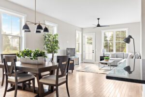 Modern, bright open-concept living and dining area at 68 Eden Lane with large windows, plants, and neutral furnishings.