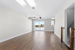 Bright empty room at 188 Alpine Drive with wood floors, modern chandelier, large window, and balcony access.