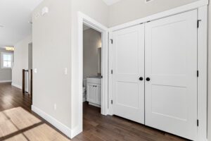 Bright hallway with wood floors and double closets at 188 Alpine Drive, open to a bathroom with a sink.