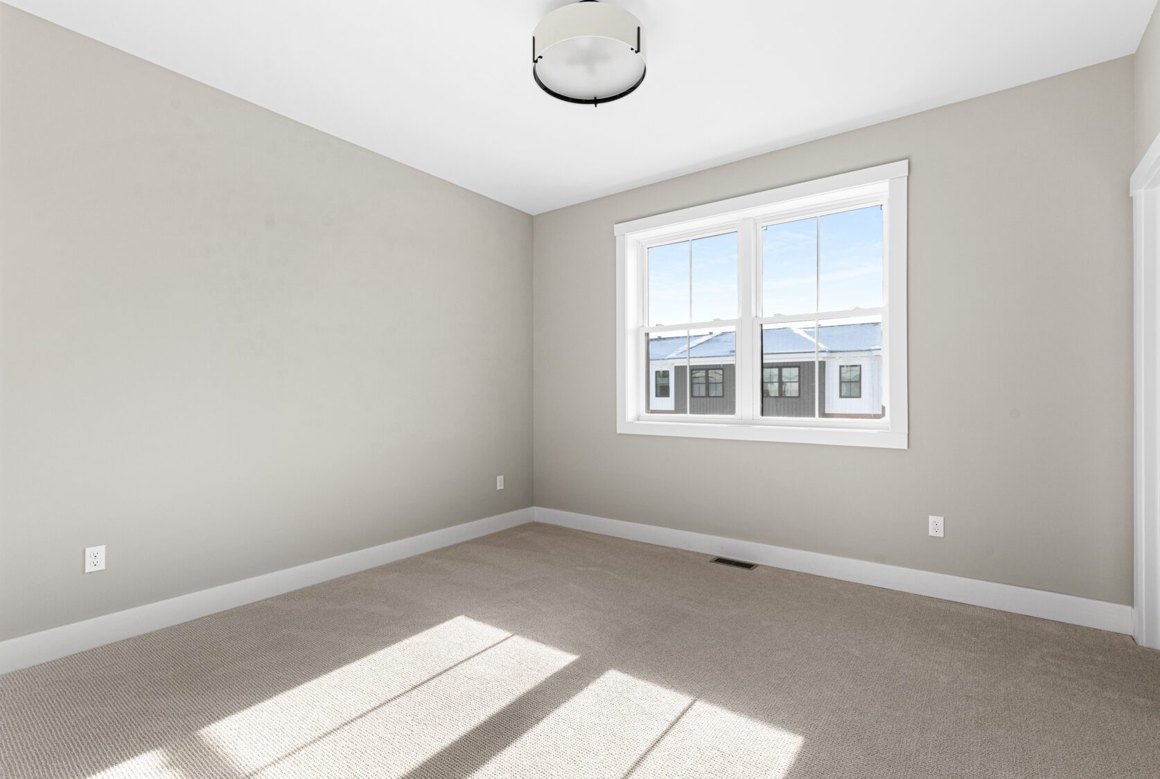 Bright, empty room at 188 Alpine Drive with beige walls, carpet flooring, large window, and modern ceiling light fixture.