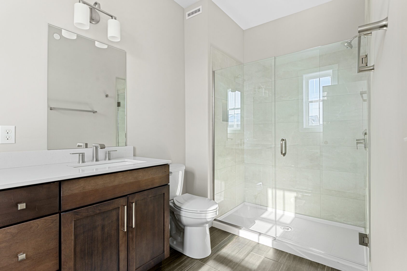Modern bathroom at 188 Alpine Drive with glass shower, wooden vanity, large mirror, and neutral-colored walls.
