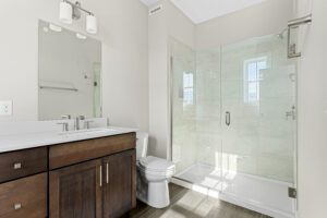 Modern bathroom at 188 Alpine Drive with glass shower, wooden vanity, large mirror, and neutral-colored walls.