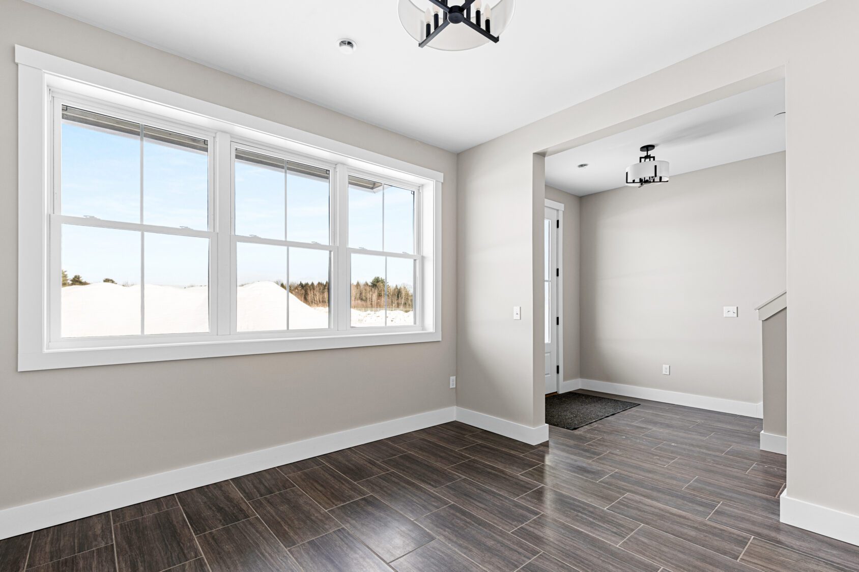 Bright, empty room with large window, beige walls, and dark wood tile flooring at 188 Alpine Drive.