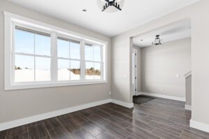 Bright, empty room with large window, beige walls, and dark wood tile flooring at 188 Alpine Drive.
