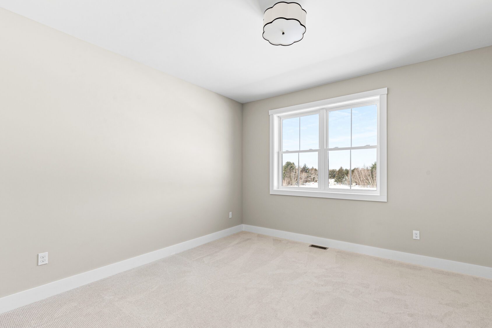 Empty beige room with carpeted floor, white trim, large window, and ceiling light fixture at 188 Alpine Drive.