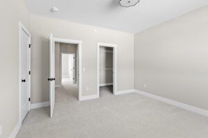 Empty beige bedroom with white trim, open door, closet, and carpeted floor at 188 Alpine Drive.