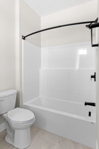 Modern bathroom at 188 Alpine Drive with a white tub, shower, curved black rod, and a white toilet.