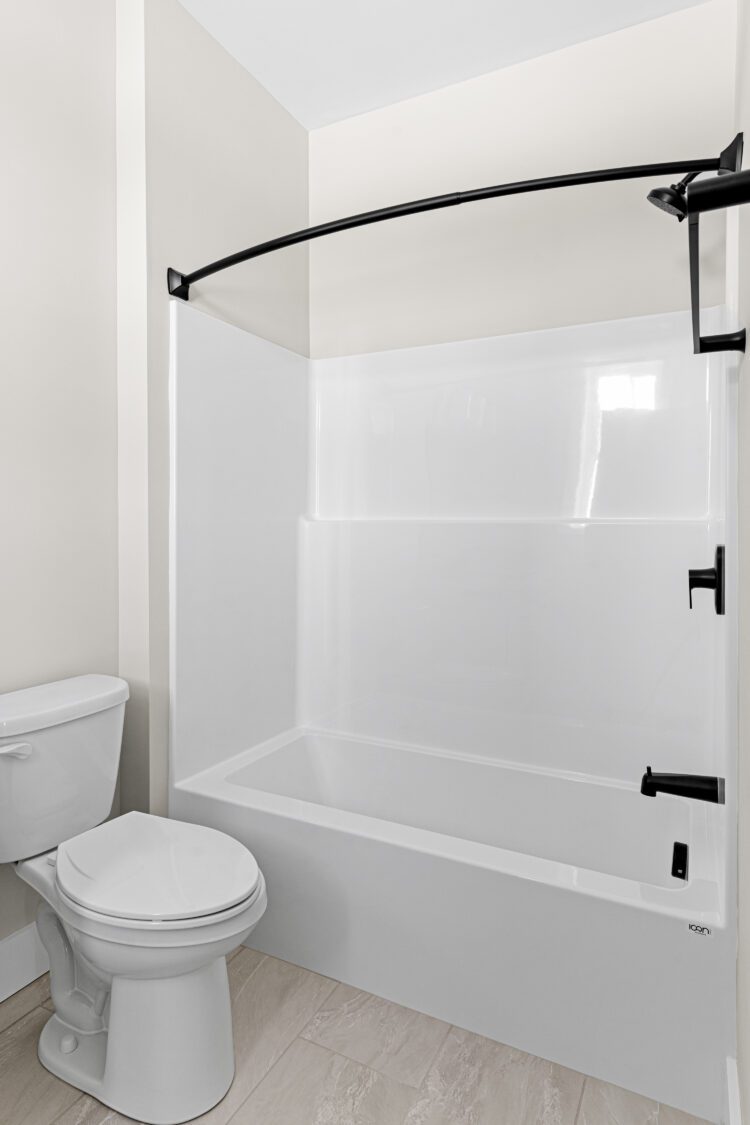 Modern bathroom at 188 Alpine Drive with a white tub, shower, curved black rod, and a white toilet.