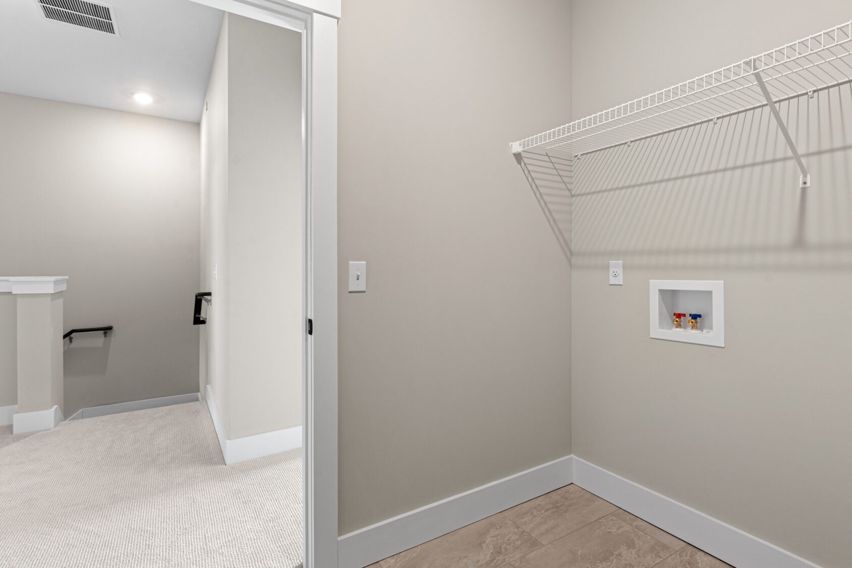 Empty laundry room at 188 Alpine Drive with wire shelf, washer hookups, tile flooring, and doorway to carpeted hallway.