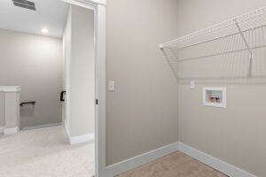 Empty laundry room at 188 Alpine Drive with wire shelf, washer hookups, tile flooring, and doorway to carpeted hallway.