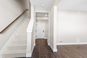 Modern entryway at 188 Alpine Drive with tiled floor, white walls, and a carpeted staircase to the upper level.