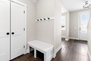 Bright entryway at 188 Alpine Drive with white bench, coat hooks, double closet doors, and a door leading outside.