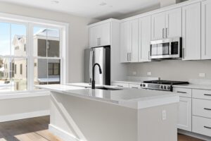 Modern kitchen at 188 Alpine Drive with white cabinets, stainless appliances, and a marble island with a black faucet.
